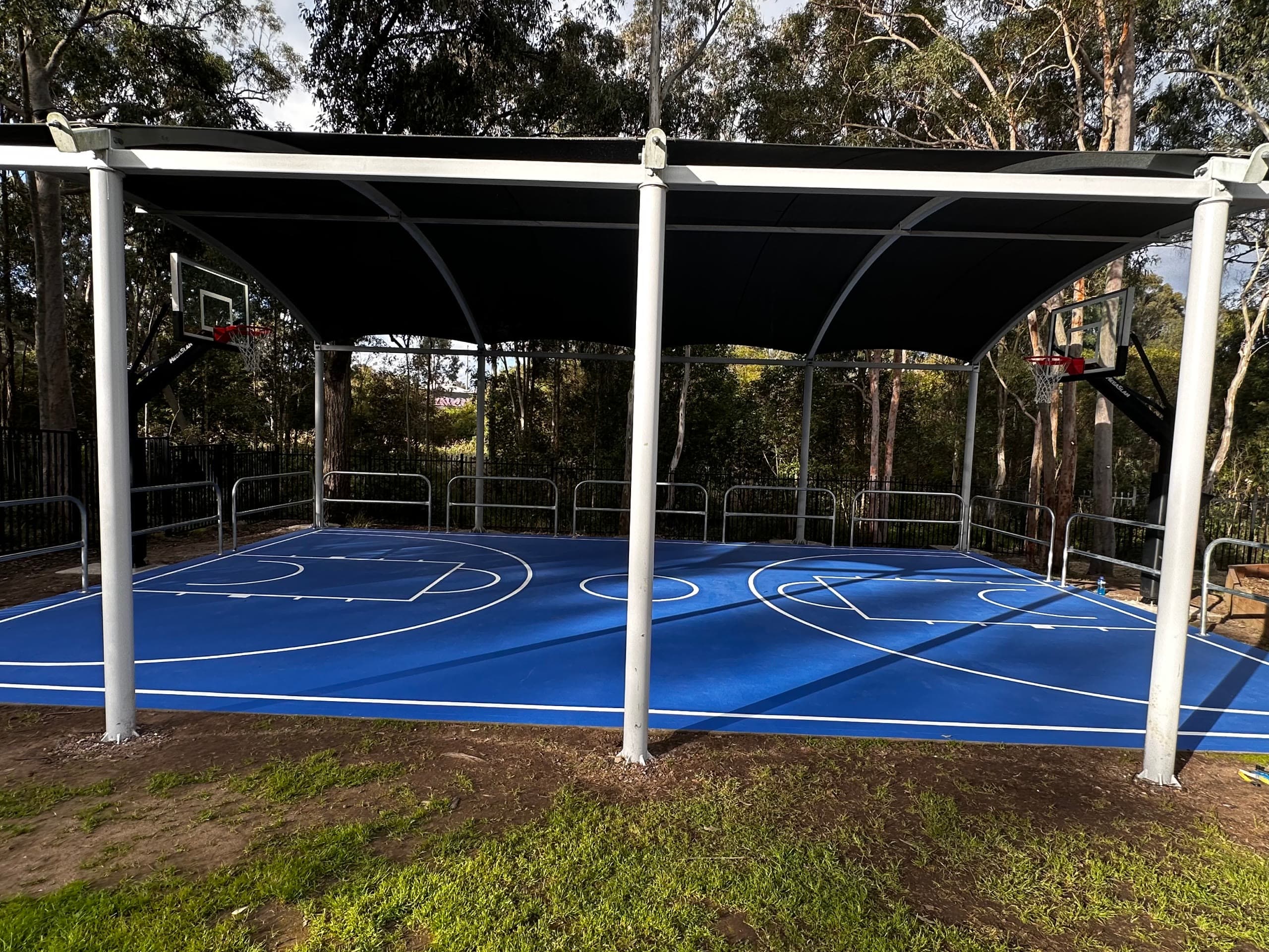 The completed basketball court at Aspect Hunter School - deep blue surface, white line marking and a covered structure over the full playing area